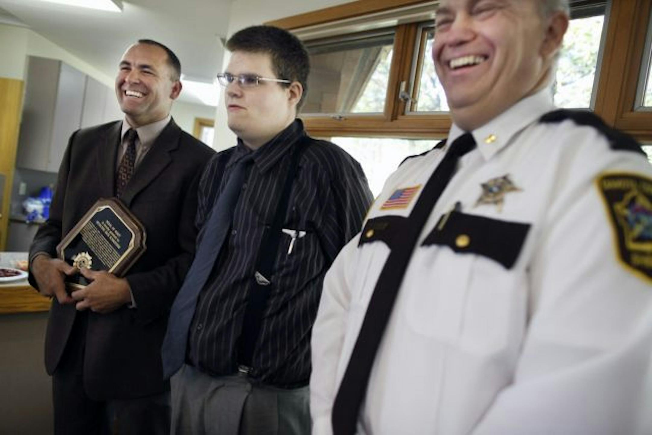 Justin Hamilton, center, posed with Detective Rick Schroeder, left, and Dakota County Sheriff Dave Bellows at an award ceremony at the Spring Lake Nature Preserve that honored the officers who helped arrest the five people who abducted and beat Hamilton. Schroeder led the investigation.