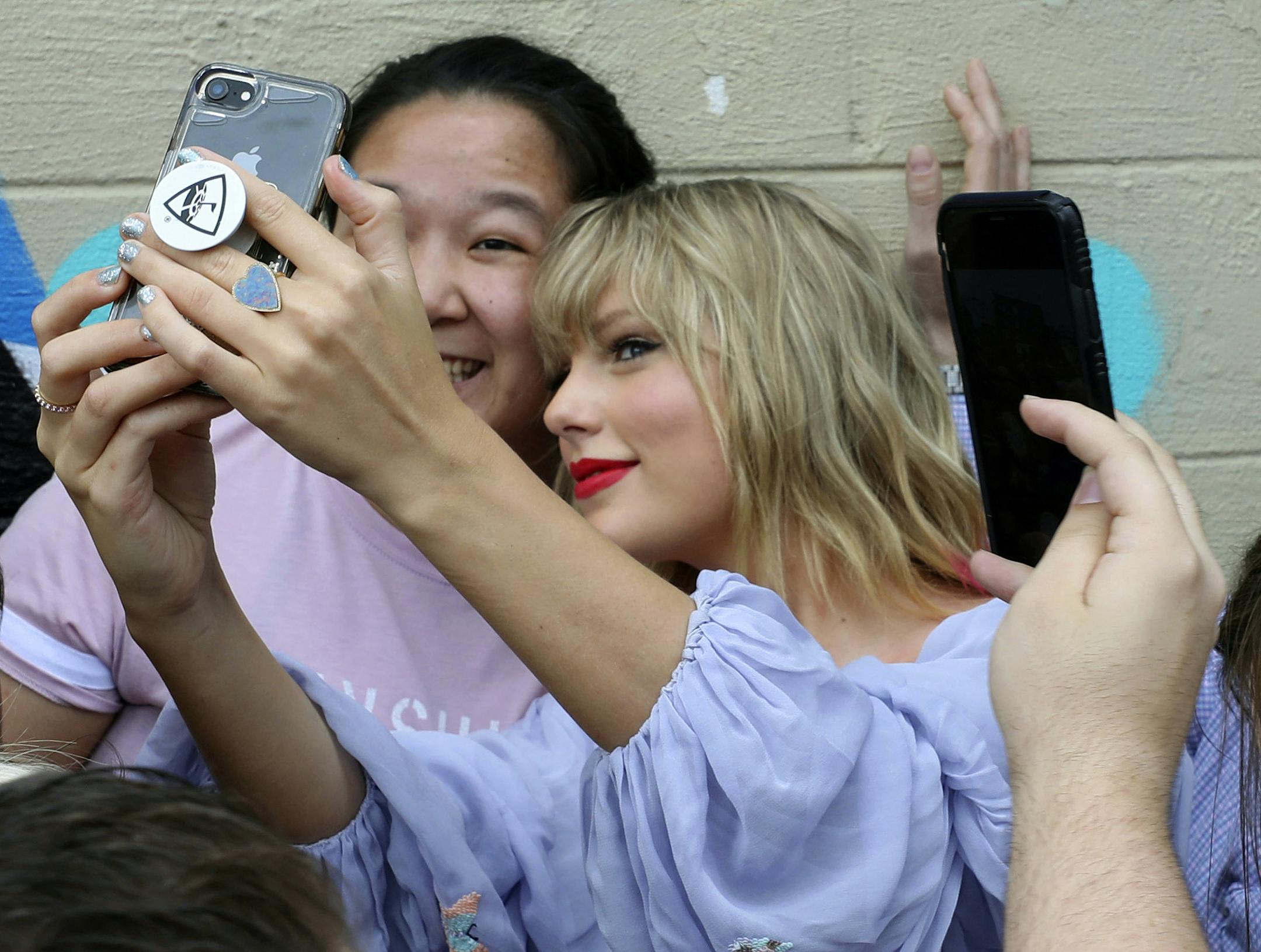 Taylor Swift takes a selfie with a fan at an appearance at a butterfly mural in the Gulch in Nashville, Tenn., on Thursday, April 25, 2019. (Alan Poizner/The Tennessean via AP)