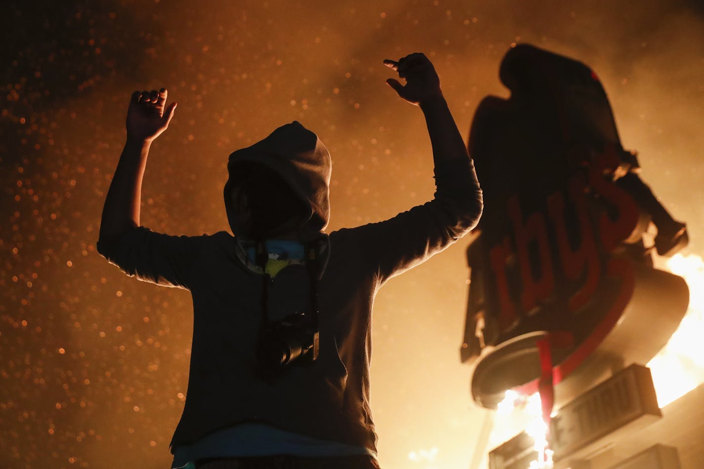 A protestor reacts beside a burning fast food restaurant near the Minneapolis 3rd Police Precinct, Friday, May 29, 2020, in Minneapolis. Protests over the death of George Floyd, a black man who died in police custody Monday, broke out in Minneapolis for a third straight night. (AP Photo/John Minchillo)