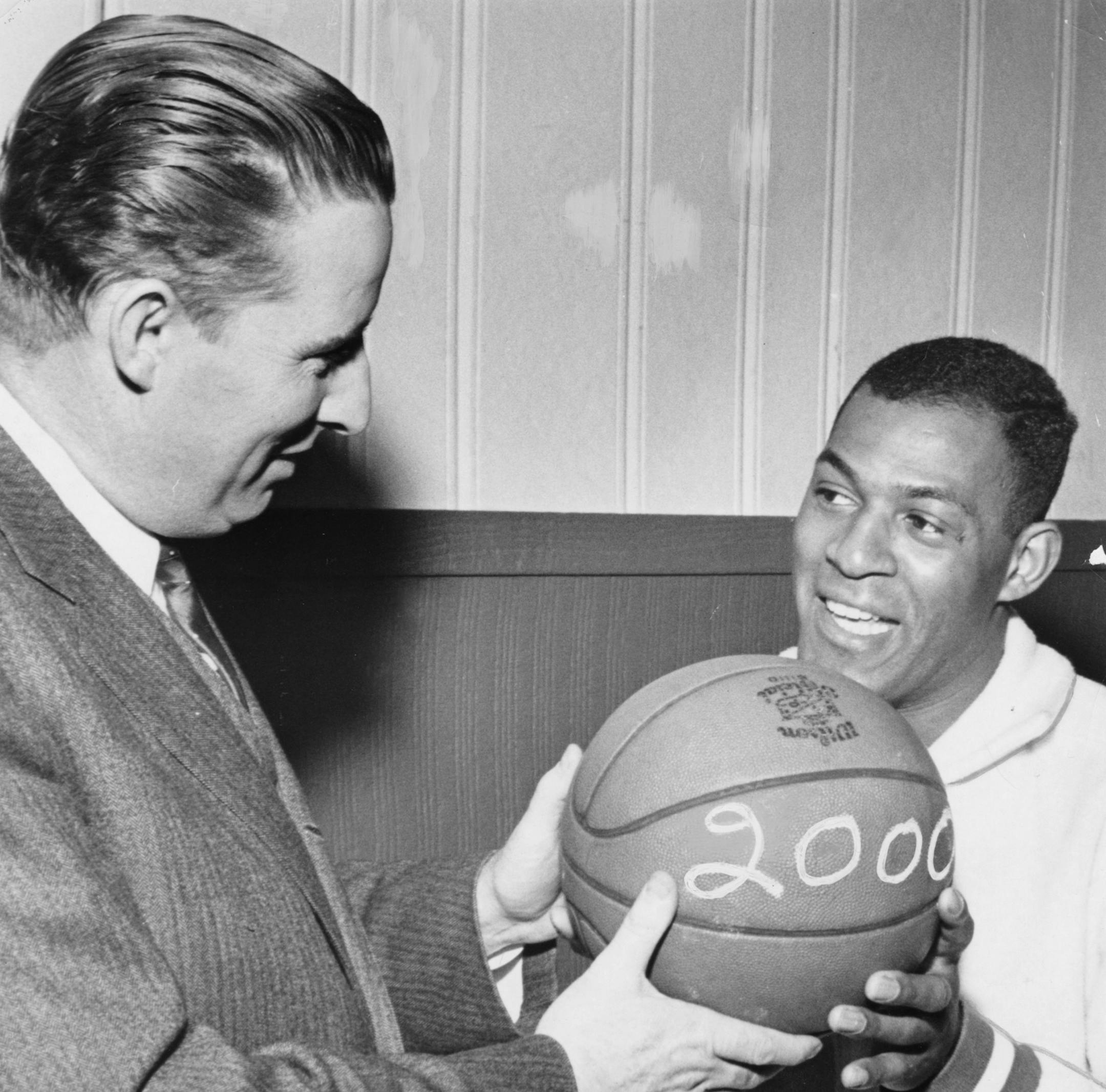 Minneapolis Lakers, 1960. Caption on back of photo: ELGIN BAYLOR FLASHES 2,000-POINT SMILE Laker President Bob Short extends congratulations. Photo by Minneapolis Star photographer Don Black, Mar. 6, 1960.