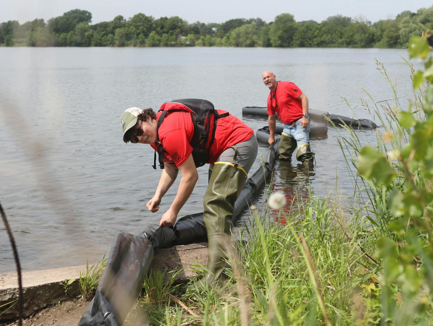 Yael Girard and Don Bates of Osprey dragged the boom into Lake Hiawatha before it was tied down around the mouth of the lake's northwest culvert.