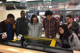 Apple Valley High School students work in groups on the laser engraver in the "Fab Lab" to create a prototype for BTM Global.