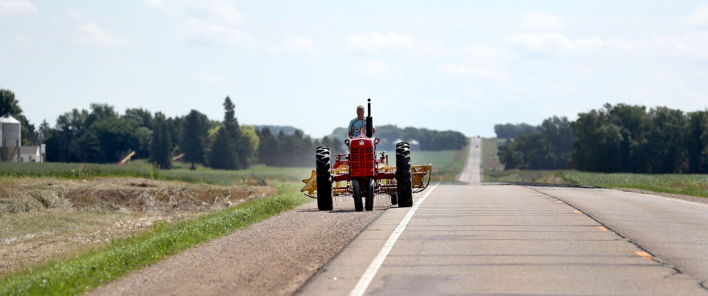 A farmer returned to his farm on Hwy. 30 after raking ditch hay with his tractor. The state wants farmers to get permits to mow ditches, hoping to preserve the grassy strips along roads for wildlife habitat. But farmers say they rely on harvesting the grass to feed livestock.