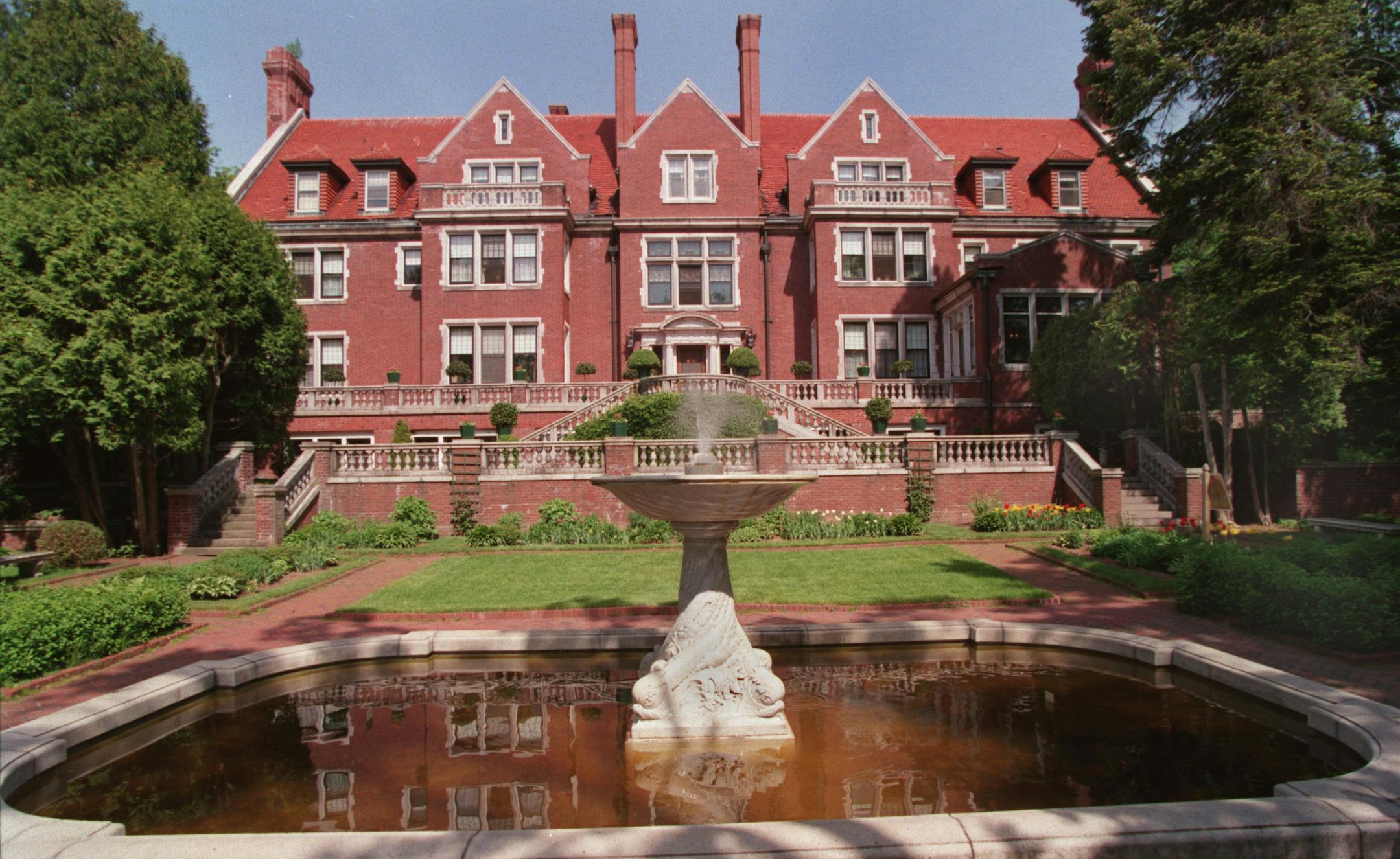 Exterior of Glensheen Mansion along the shore of London Rd in Duluth, as seen from the lake -side, with fountain and gardens in the foreground.