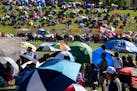 People hold umbrellas to block the sun while watching a soccer game in 2017 at the Hmong Freedom Celebration Festival in St. Paul.