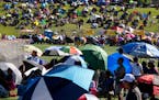 People hold umbrellas to block the sun while watching a soccer game in 2017 at the Hmong Freedom Celebration Festival in St. Paul.