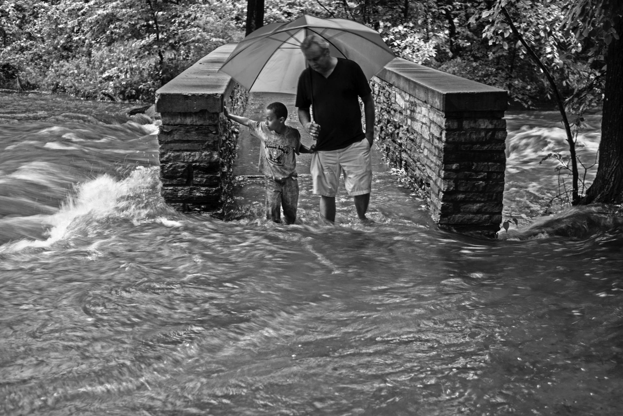 [ MARK VANCLEAVE * mark.vancleave@startribune.com * WX062014 * 262621 Heavy rain caused flooding along Minnehaha Creek in Minneapolis on Thursday, Jun 19, 2014. rain weather minneapolis storm flood minnesota ] Craig Susag and his grandson Nethaniel cross a flooded bridge over Minnehaha Creek in Minnehaha Park. ORG XMIT: MIN1406192256191430
