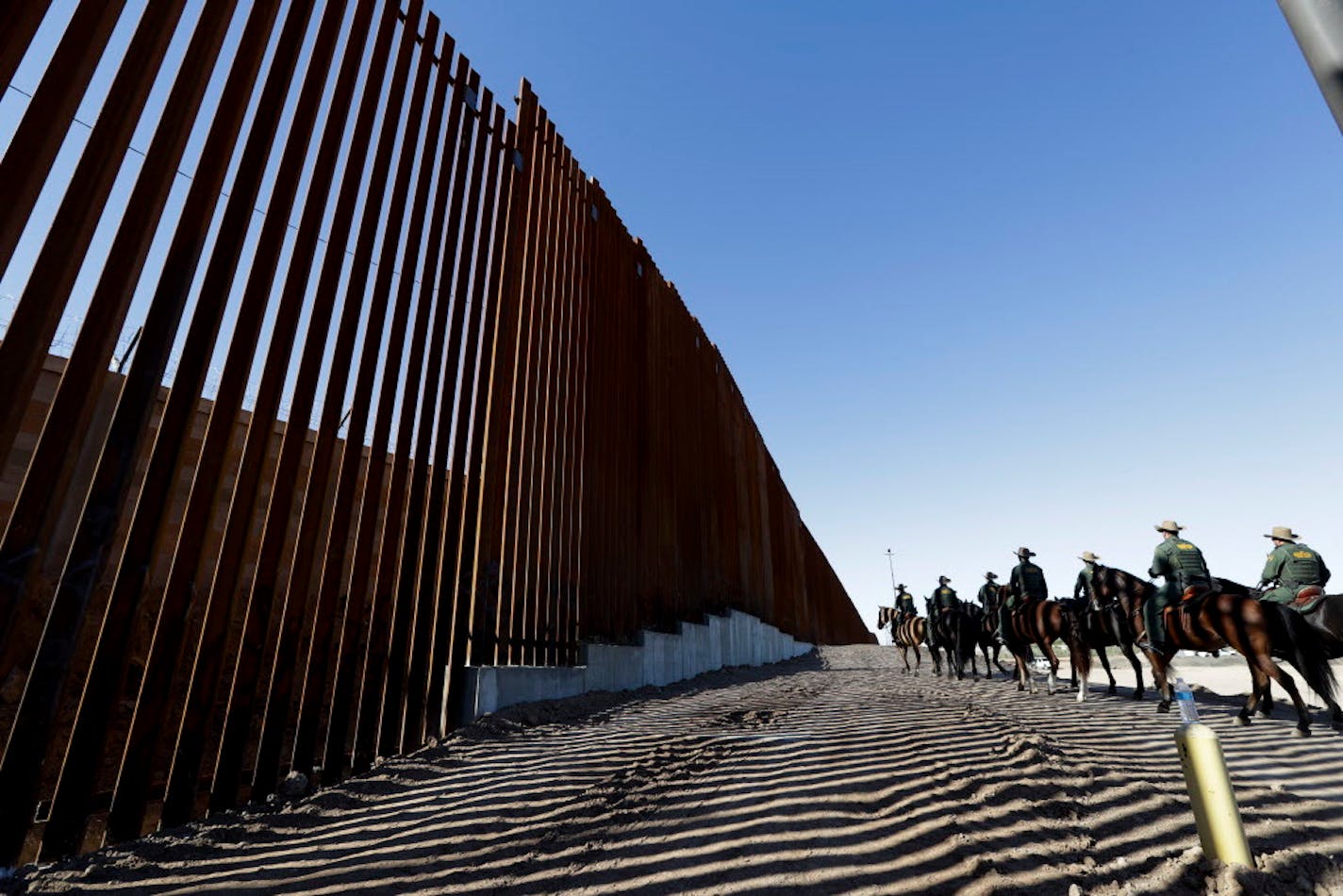 Mounted Border Patrol agents ride along a newly fortified border wall structure Friday, Oct. 26, 2018, in Calexico, Calif. (AP Photo/Gregory Bull)