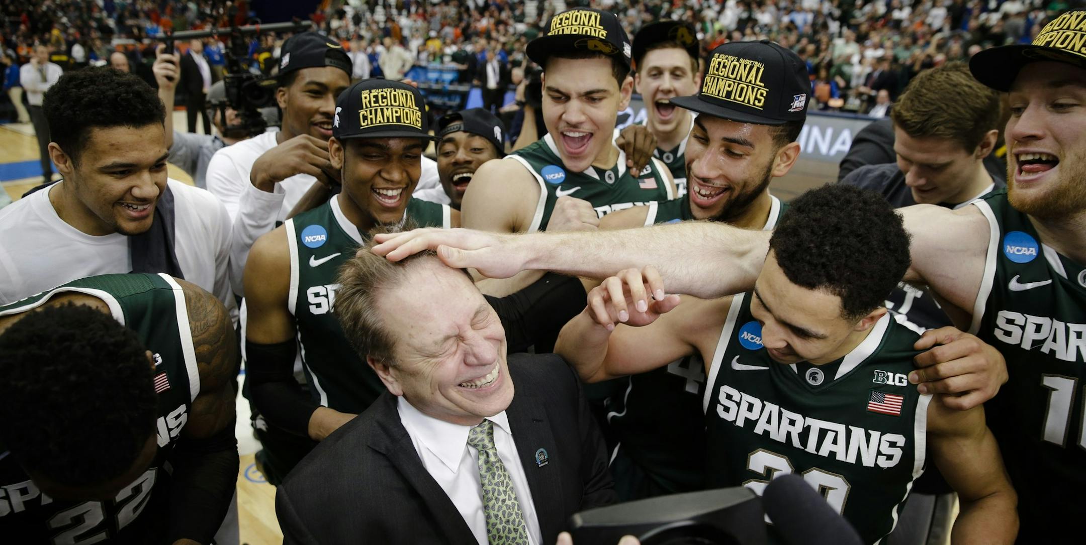 Michigan State head coach Tom Izzo, center front, celebrates with his team after the regional final against Louisville in the NCAA men's college basketball tournament Sunday, March 29, 2015, in Syracuse, N.Y. Michigan State won the game 76-70. (AP Photo/Seth Wenig)