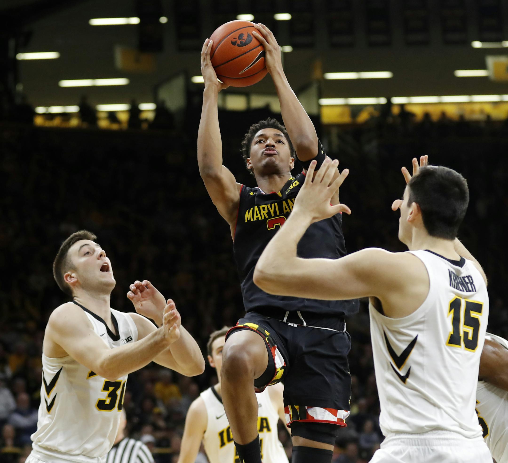 Maryland guard Aaron Wiggins, center, drives to the basket between Iowa's Connor McCaffery, left, and Ryan Kriener, right, during the first half of an NCAA college basketball game Tuesday, Feb. 19, 2019, in Iowa City, Iowa. (AP Photo/Charlie Neibergall)