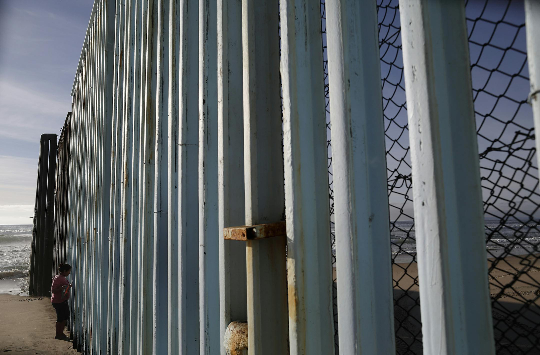 A woman looks through the border structure separating San Diego, right, from Tijuana, Mexico, Wednesday, Feb. 1, 2017, in Tijuana. President Donald Trump threatened in a phone call with his Mexican counterpart to send U.S. troops to stop "bad hombres down there" unless the Mexican military does more to control them, according to an excerpt of a transcript of the conversation obtained by The Associated Press. (AP Photo/Gregory Bull) ORG XMIT: MIN2017022312173615