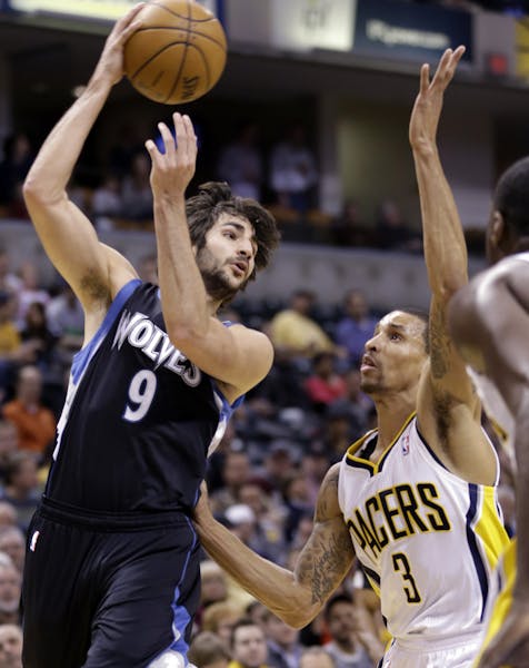 Timberwolves guard Ricky Rubio, left, passes over Indiana Pacers guard George Hill