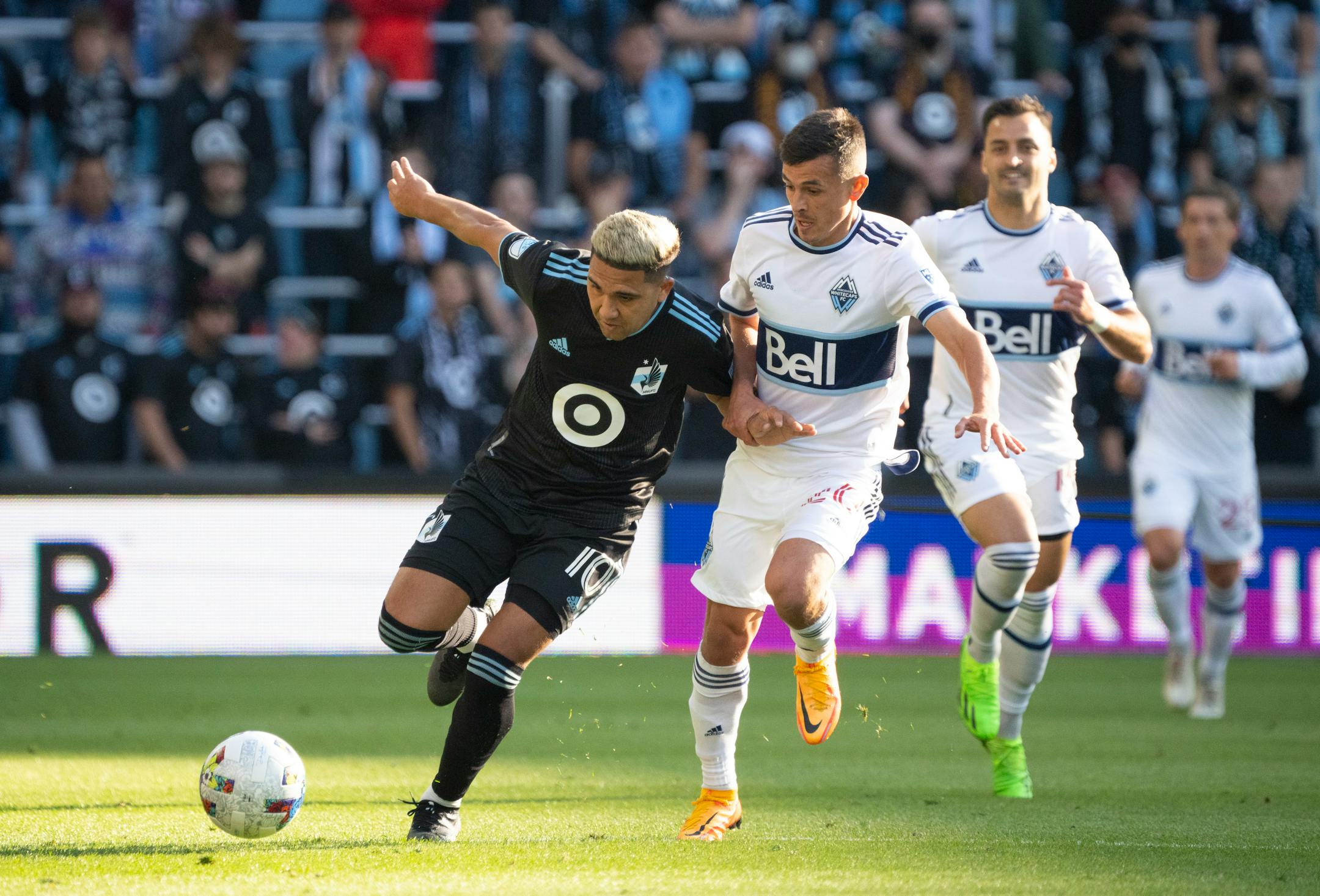 Minnesota United midfielder Emanuel Reynoso (10) pursued the ball as he was held by Vancouver Whitecaps midfielder Andr's Cubas (20) in the first half.