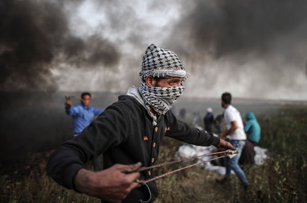 A Palestinian protester uses a slingshot to throw stones toward Israeli forces during clashes following a protest along the border with Israel, east o