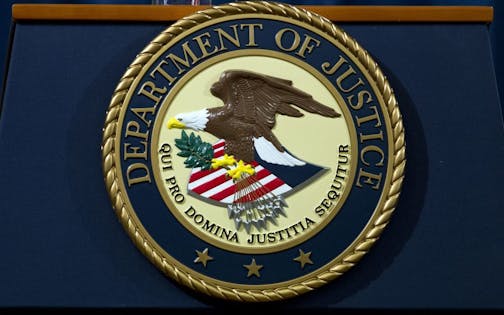 The Department of Justice seal is seen, ahead of a news conference of Deputy Attorney General Rod Rosenstein speaks announcing the indictment against international computer hacking, at Department of Justice in Washington, Wednesday, Nov. 28, 2018. The Justice Department says two Iranian computer hackers have been charged in connection with multimillion-dollar cybercrime and extortion scheme that targeted U.S. government agencies and businesses.