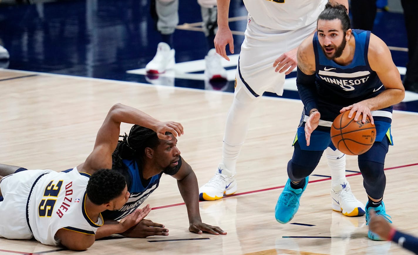 Minnesota Timberwolves guard Ricky Rubio, right, picks up a loose ball after Denver Nuggets guard PJ Dozier, left front, lost control while tangling with Timberwolves center Naz Reid.