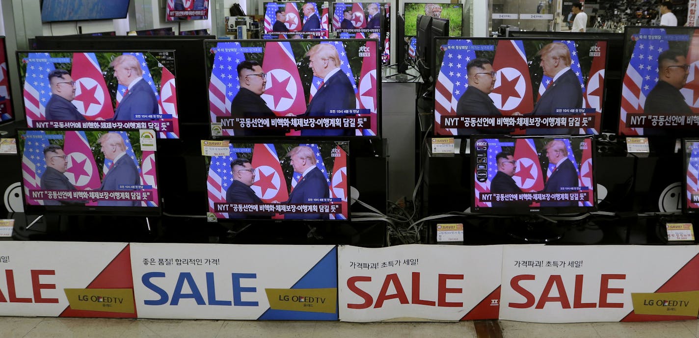 TV screens shows U.S. President Donald Trump, right, meets with North Korean leader Kim Jong Un in Singapore during a news program, at Yongsan Electronic store in Seoul, South Korea, South Korea, Tuesday, June 12, 2018. (AP Photo/Ahn Young-joon)