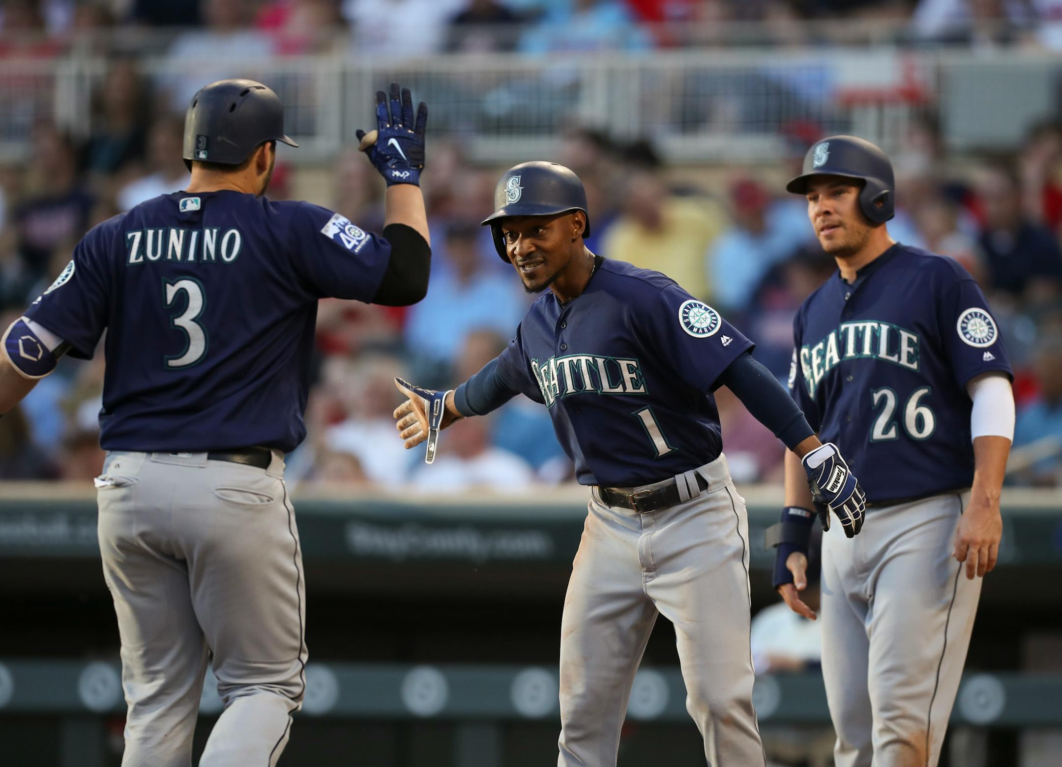 Seattle's Jarrod Dyson (1) and Danny Valencia (26) greeted teammate Mike Zunino at home after his three run homer in the third inning put the Mariners ahead of the Twins 5-0.