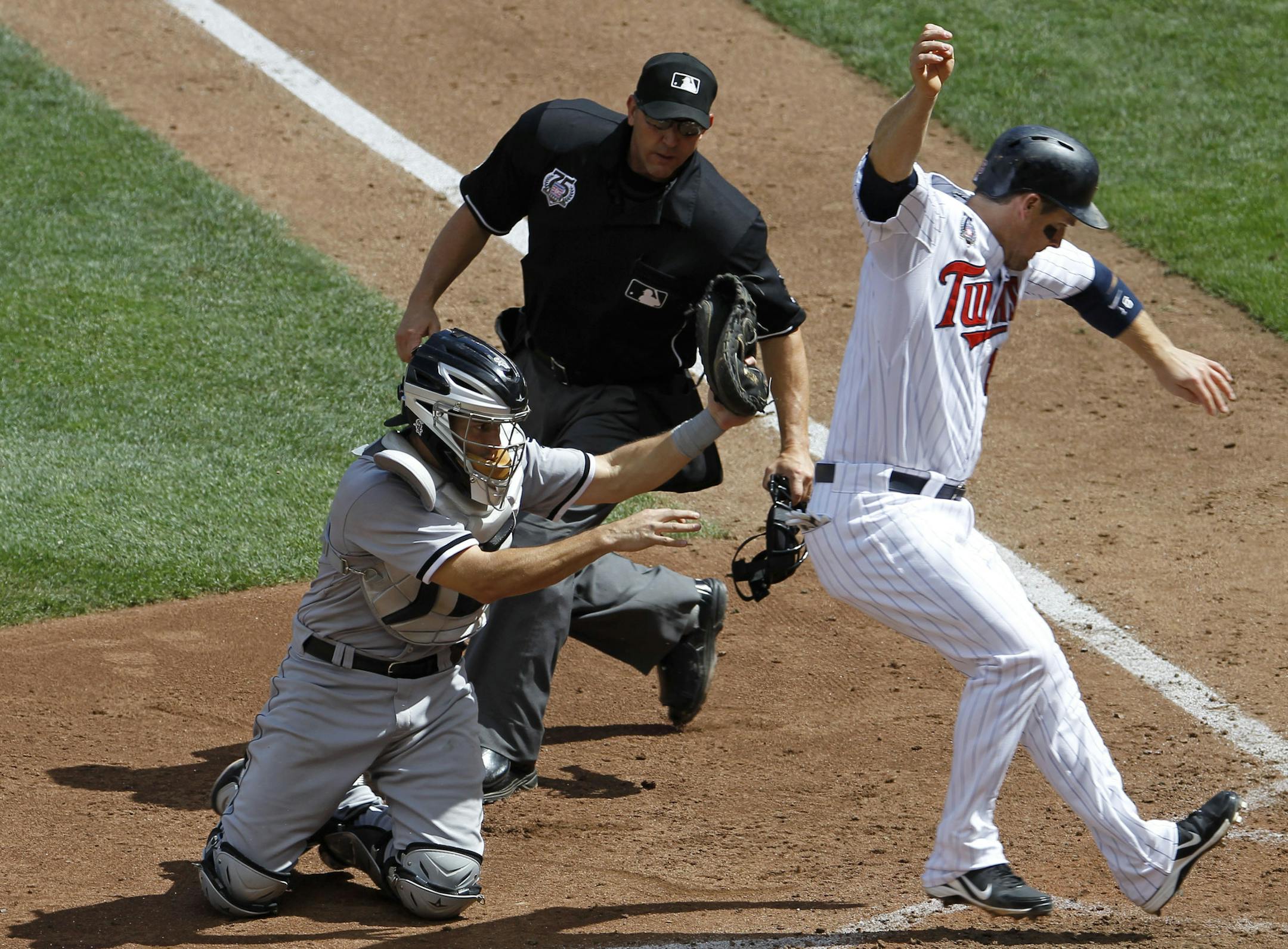 Minnesota Twins' Josh Willingham, right, scores from third base on a sacrifice fly by Danny Santana as Chicago White Sox catcher Adrian Nieto, left, applies the tag without the ball during the seventh inning of a baseball game in Minneapolis, Sunday, July 27, 2014. Looking to make the call is home plate umpire Jeff Kellogg. The Twins won 4-3. (AP Photo/Ann Heisenfelt)