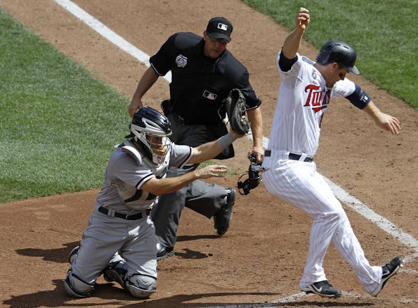 Minnesota Twins' Josh Willingham, right, scores from third base on a sacrifice fly by Danny Santana as Chicago White Sox catcher Adrian Nieto, left, a