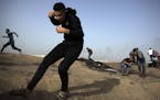 Palestinian protesters run for cover from gunfire by Israeli troops during a protest at the Gaza Strip's border with Israel, Friday, May 25, 2018. (AP