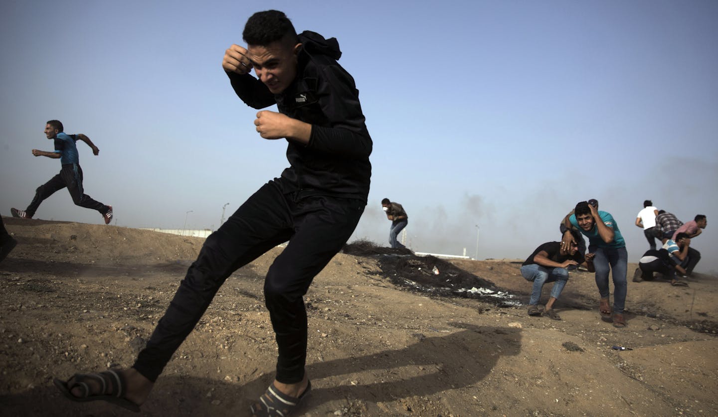 Palestinian protesters run for cover from gunfire by Israeli troops during a protest at the Gaza Strip's border with Israel, Friday, May 25, 2018. (AP Photo/Khalil Hamra)