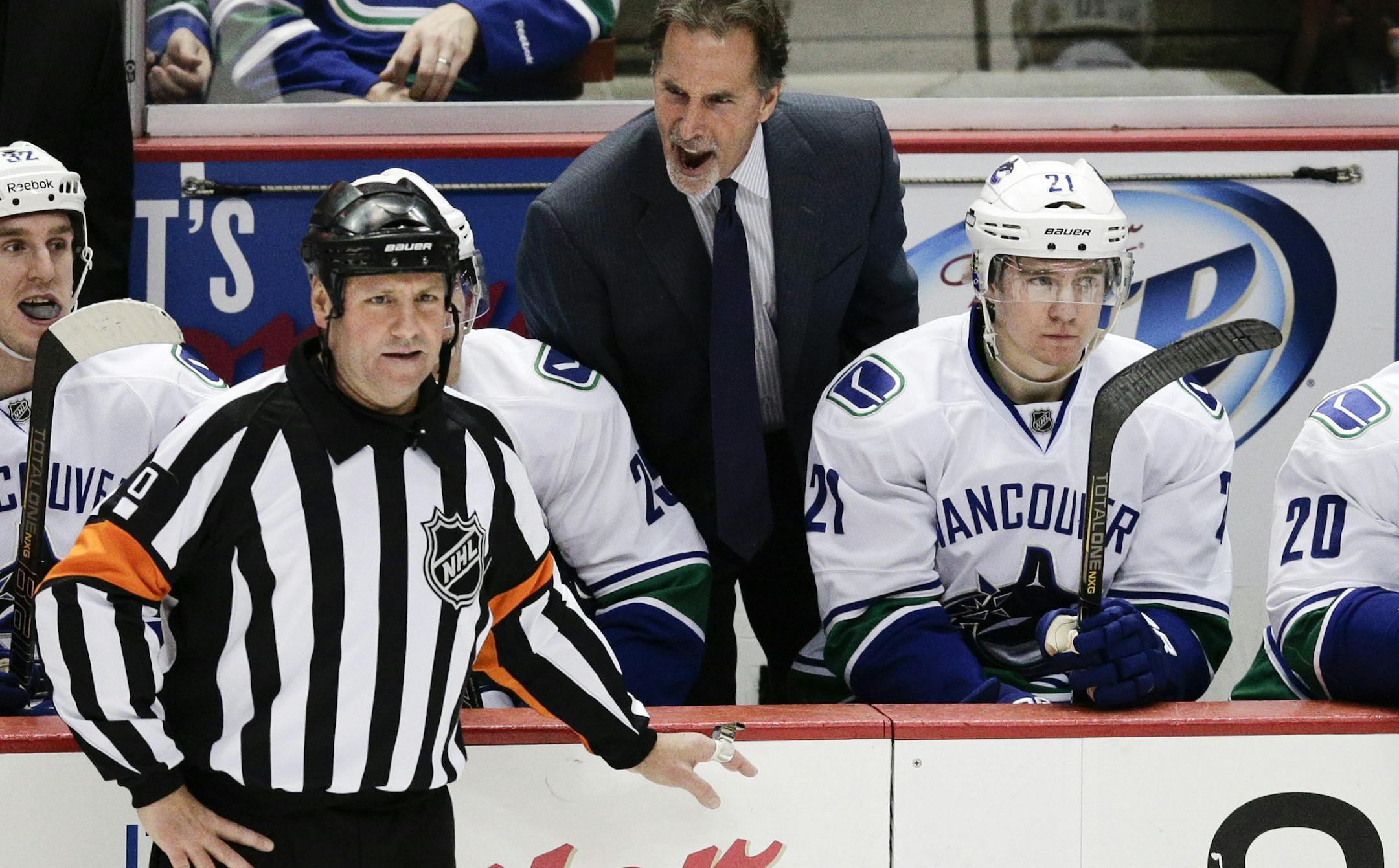 Vancouver Canucks head coach John Tortorella, center, yells to referee Paul Devorski during the third period of an NHL hockey game against the Anaheim Ducks on Wednesday, Jan. 15, 2014, in Anaheim, Calif. The Ducks won 9-1. (AP Photo/Jae C. Hong) ORG XMIT: CAJH117