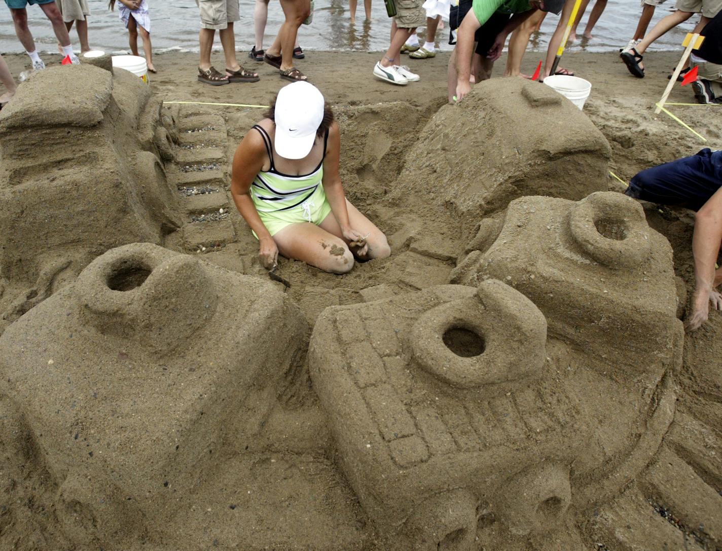 Renee Jones/Star Tribune 7/24/05 Lynn Cole works on a sand castle called "The Potty Train" with her family at the aquatennial celebration sand castle competition Sunday at Lake Calhoun. The Cole family of Stewartville, with help from a few friends, designed the train to make it look like it was a steam engine with smoke by using dry ice in the cup built into the engine.