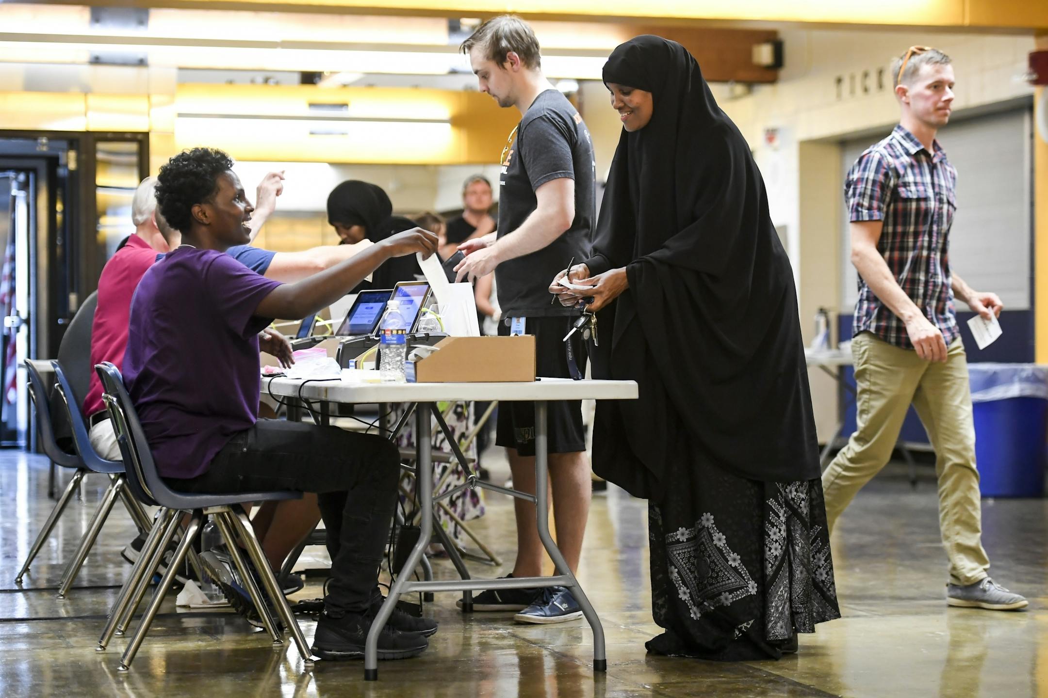 Election judge Nasradin Kewden, 17, helped Khadijo Khalif as she confirmed her registration Tuesday night during primary voting at Edison High School in Northeast Minneapolis.
