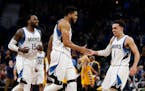 Minnesota Timberwolves teammates Karl-Anthony Towns, center, and Tyus Jones (1) celebrate their lead in the second half of an NBA basketball game Sund