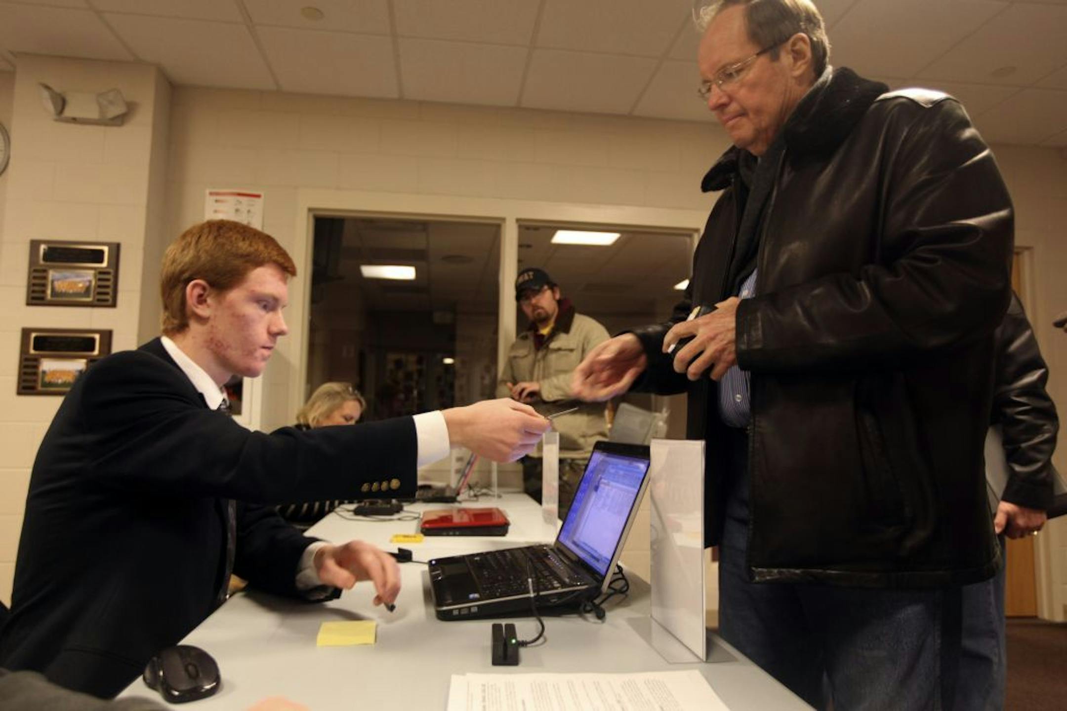 Henry Stachyra Jr. handed back John Luoma's id after scanning it at the Republican caucus at Rutherford Elementary School in Stiilwater Min., Tuesday, February 7, 2012.