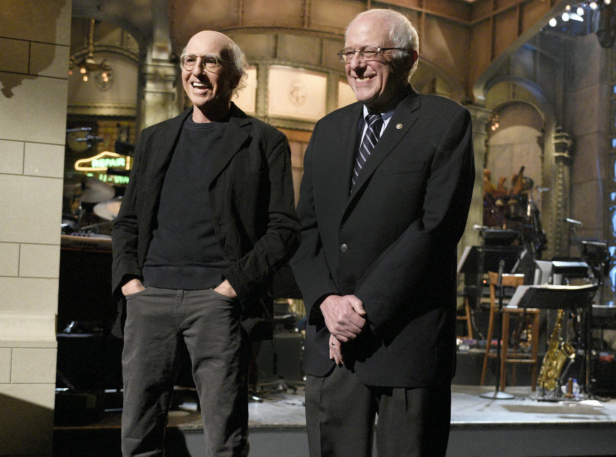 This Saturday, Feb. 6, 2016 photo provided by NBC shows, Larry David, left, and Democratic presidential candidate Sen. Bernie Sanders, introducing musical guest The 1975 on the "Larry David" episode of "Saturday Night Live," in New York. Sanders made a cameo appearance on "Saturday Night Live" three days before the New Hampshire primary, appearing in a skit with host David, the comic who has done a dead-on impersonation of him. Sanders is the third presidential candidate to appear on "SNL" this