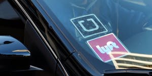 In this Tuesday, Jan. 12, 2016 photo, a driver displaying Lyft and Uber stickers on his front windshield drops off a customer in downtown Los Angeles.