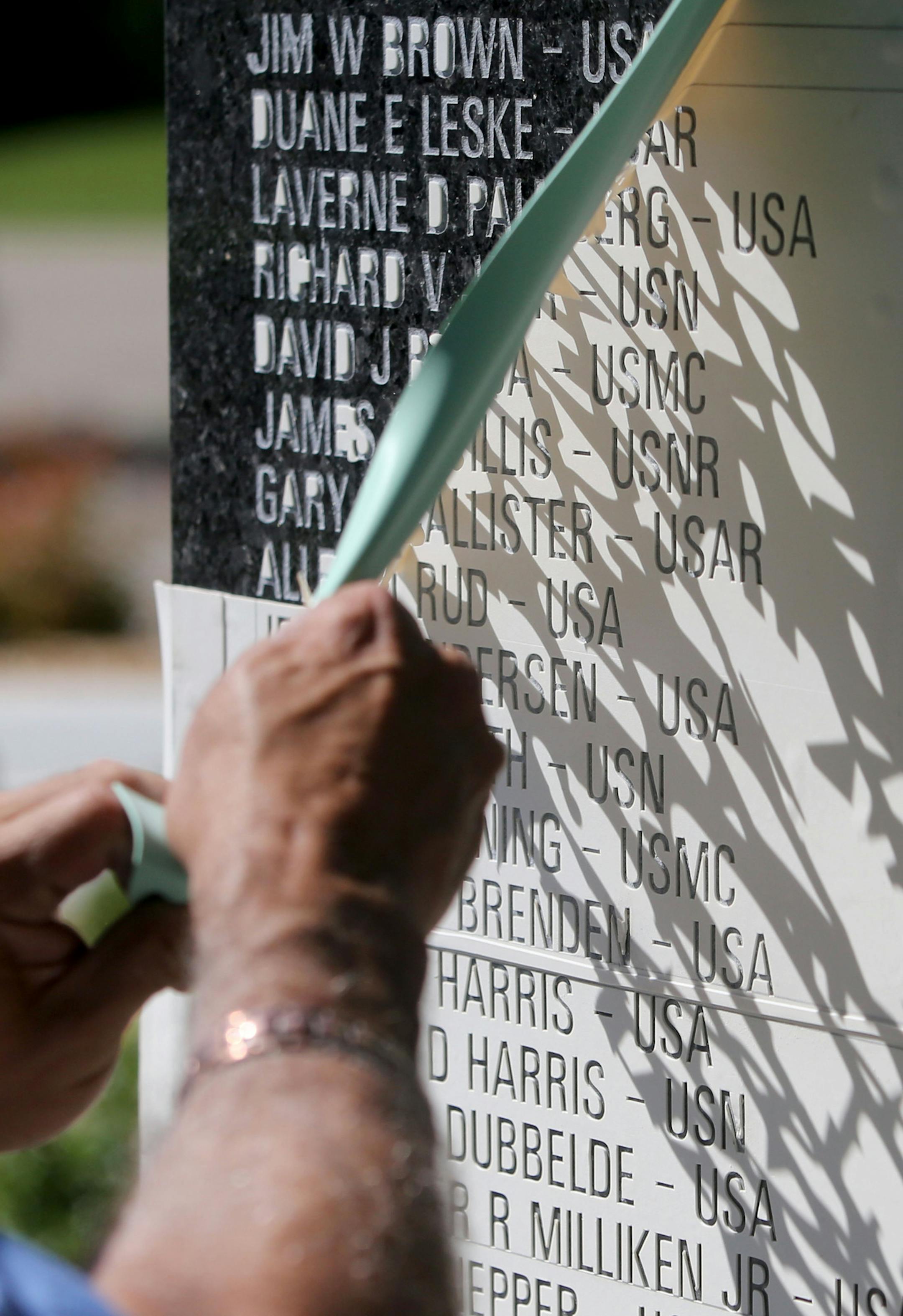 Engraver Wayne Winkelman, who owns and operates Winkelman Cemetery Lettering in St. Cloud, removes the rubber template he used to snad blast the names of the first to go onto the Minnesota black granite Memorial Tuesday, June 16, 2015, near the southwest corner of the Hilde Performance Center at 3500 Plymouth Blvd. in Plymouth, MN. ](DAVID JOLES/STARTRIBUNE)djoles@startribune.com Plymouth is honoring area veterans with a new memorial that will be unveiled this month. Crews started work on engrav