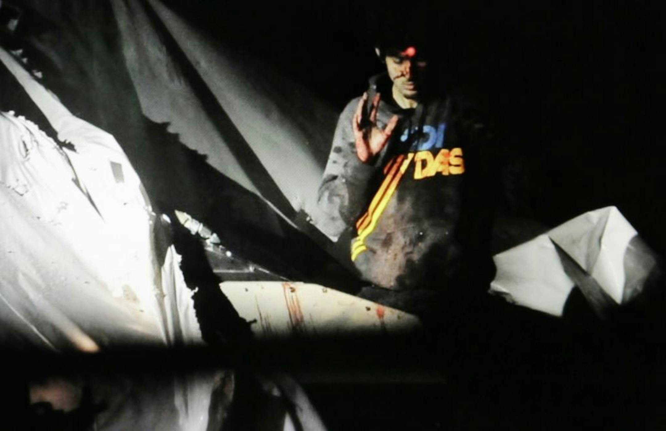 In this Friday, April 19, 2013 Massachusetts State Police photo, 19-year-old Boston Marathon bombing suspect Dzhokhar Tsarnaev, bloody and disheveled with the red dot of a sniper's rifle laser sight on his forehead, raises his hand from inside a boat at the time of his capture by law enforcement authorities in Watertown, Mass.