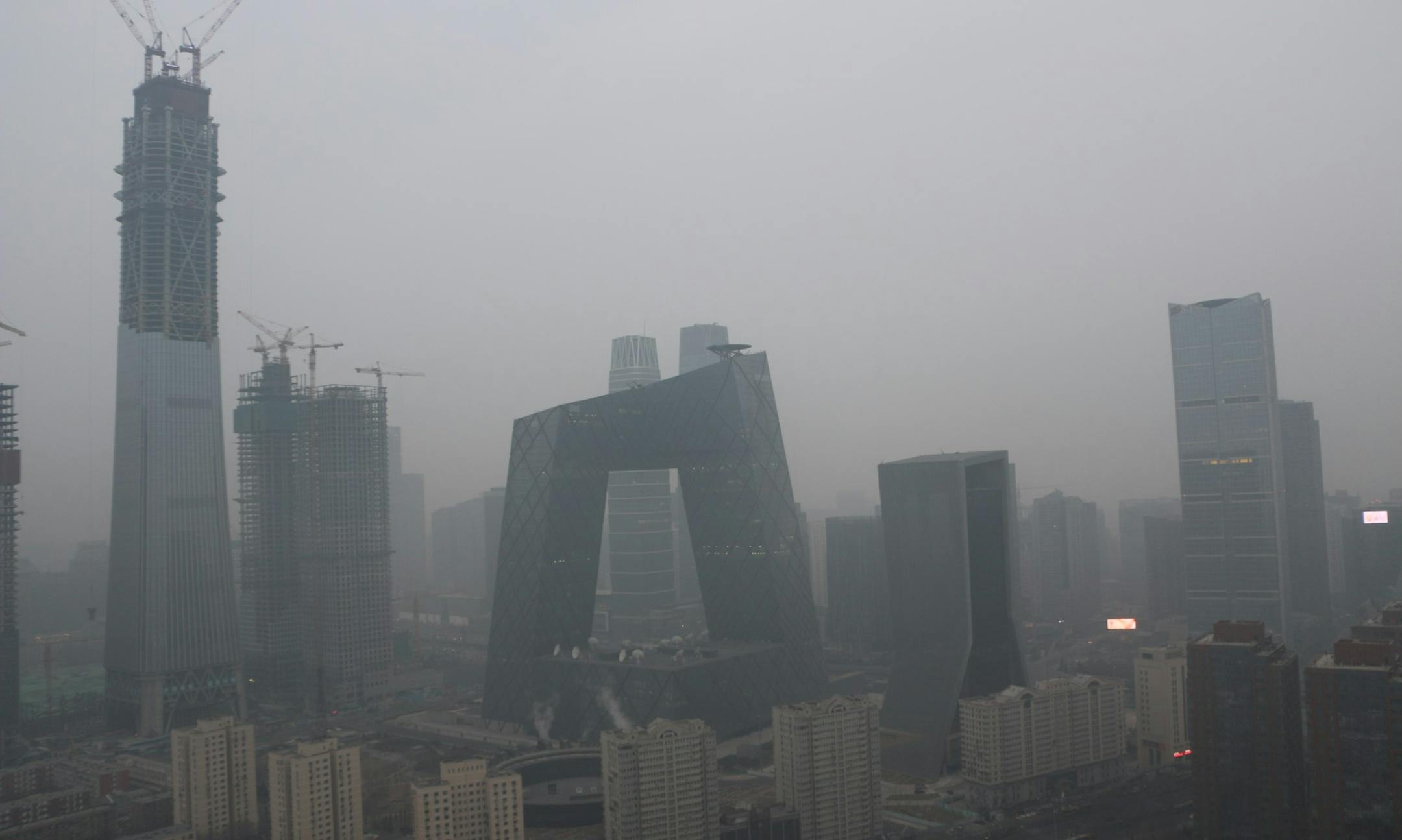 --FILE--The CCTV Tower, center, and other high-rise buildings are seen vaguely in heavy smog in Beijing, China, 7 January 2017. Beijing filed 13,127 environmental protection violation cases in 2016, with fines totaling 150 million yuan (US$21.8 million), local environmental authorities said on Wednesday (11 January 2017). A total of 10,184 cases, involving fines of 8.7 million yuan, were due to pollution from mobile emission sources. Of these, more than 10,000 vehicles were punished for excessiv
