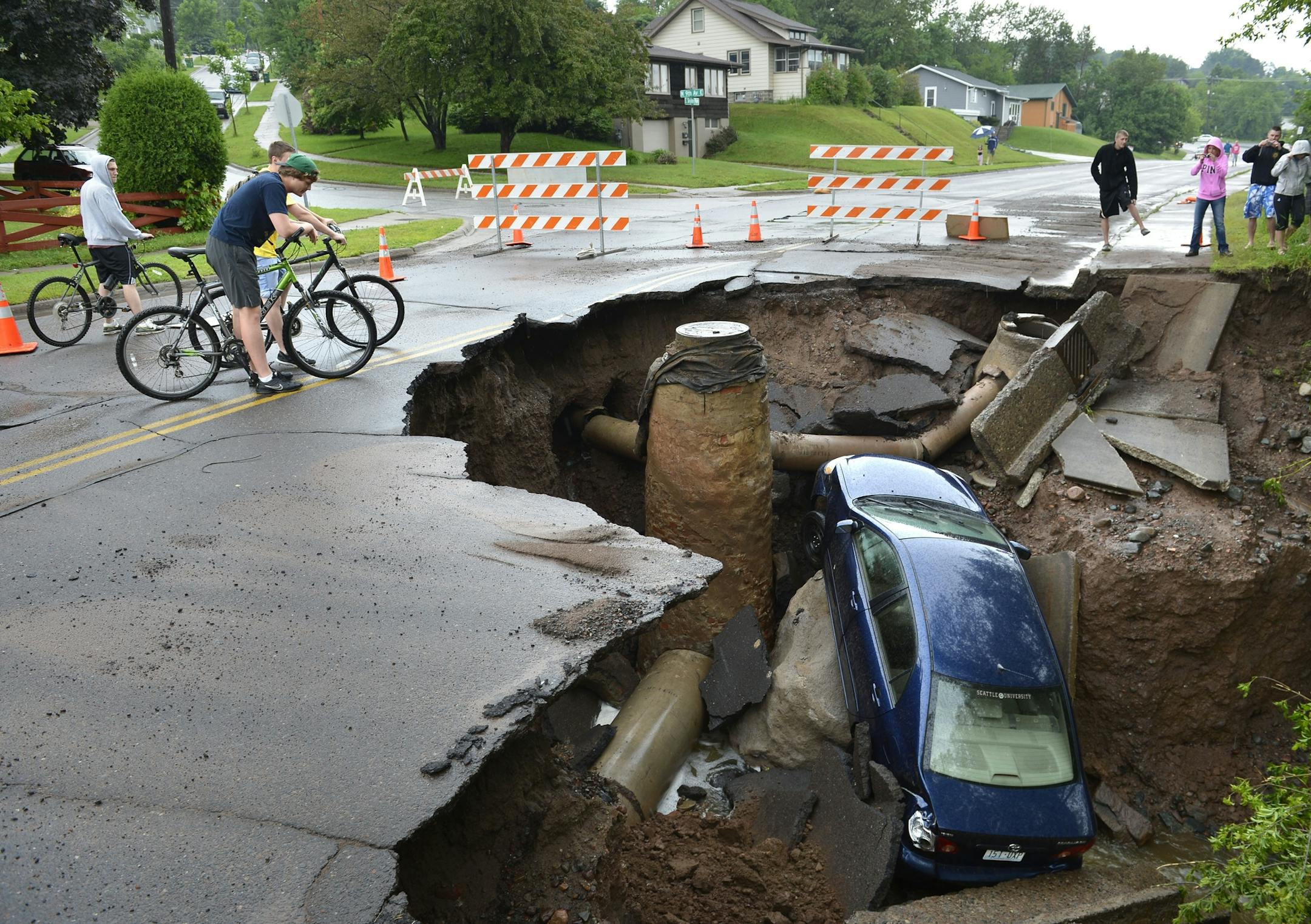 A car sits in a giant sinkhole in Duluth, Minn. Wednesday, June 20, 2011. Residents evacuated their homes and animals escaped from pens at a zoo as floods fed by a steady torrential downpour struck northeastern Minnesota, inundating the city of Duluth, officials said Wednesday. (AP Photo/The Star Tribune, Brian Peterson) MANDATORY CREDIT; ST. PAUL PIONEER PRESS OUT; MAGS OUT; TWIN CITIES TV OUT