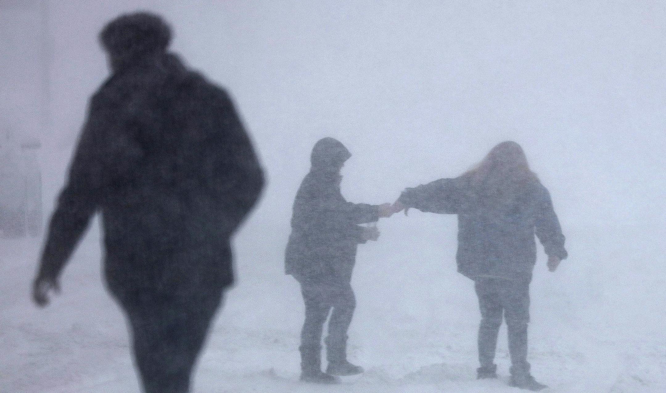 People try to cross 3rd Ave. in Anoka, Minn., Wednesday morning, Feb. 20, 2019, in the snow. Forecasters are warning residents in parts of Minnesota and western Wisconsin the advancing winter storm could produce up to 9 inches of snow. (David Denney/Star Tribune via AP)