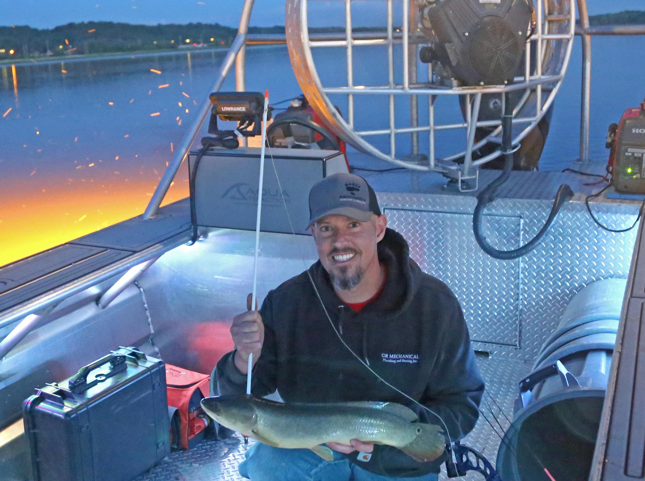 Patrick Kirschbaum of Rogers with a dogfish he arrowed while bowfishing on the Mississippi River just downriver from St. Paul on Wednesday night.