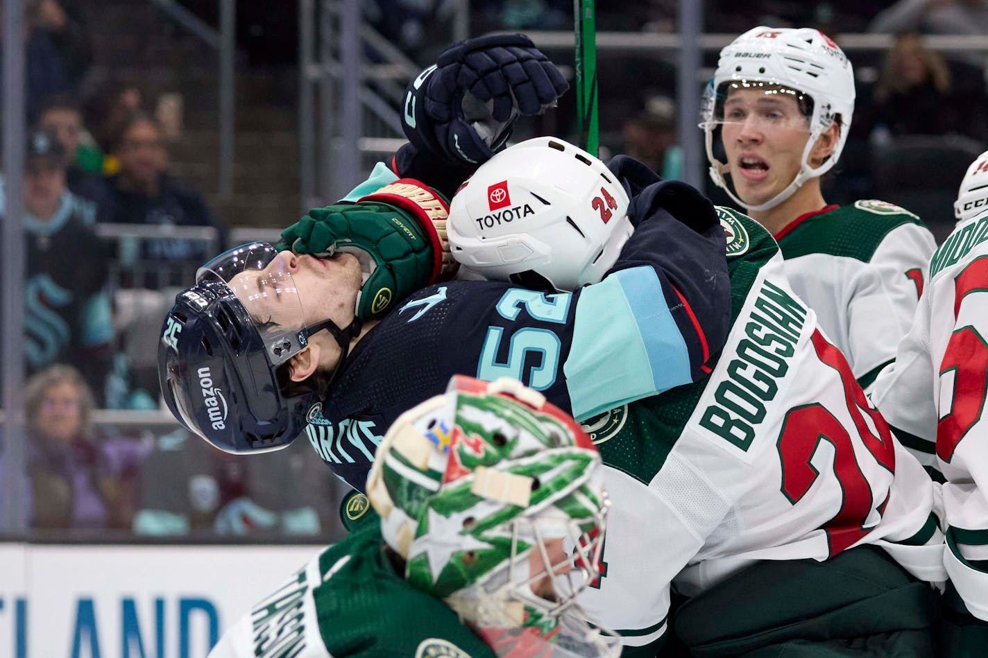 Seattle Kraken left wing Tye Kartye (52) and Minnesota Wild defenseman Zach Bogosian (24) fight at the goal during the Third period of an NHL hockey game, Sunday, Dec. 10, 2023, in Seattle. (AP Photo/John Froschauer)