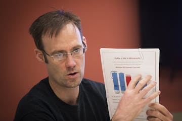 Matt Toburen, the public policy director of the Minnesota AIDS Project, leads a meeting with activists while holding up a sheet with stats about AIDS 