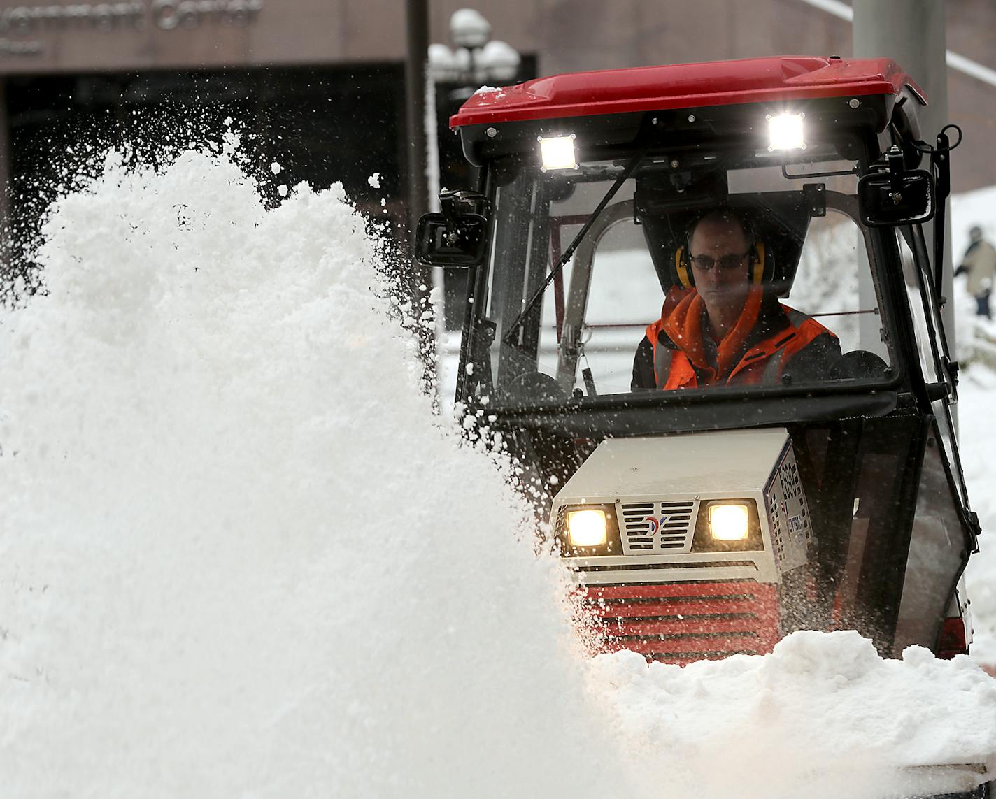 A worker cleared snow Friday in front of the Hennepin County Government Center in downtown Minneapolis after almost 6 inches fell overnight. More is falling Saturday.