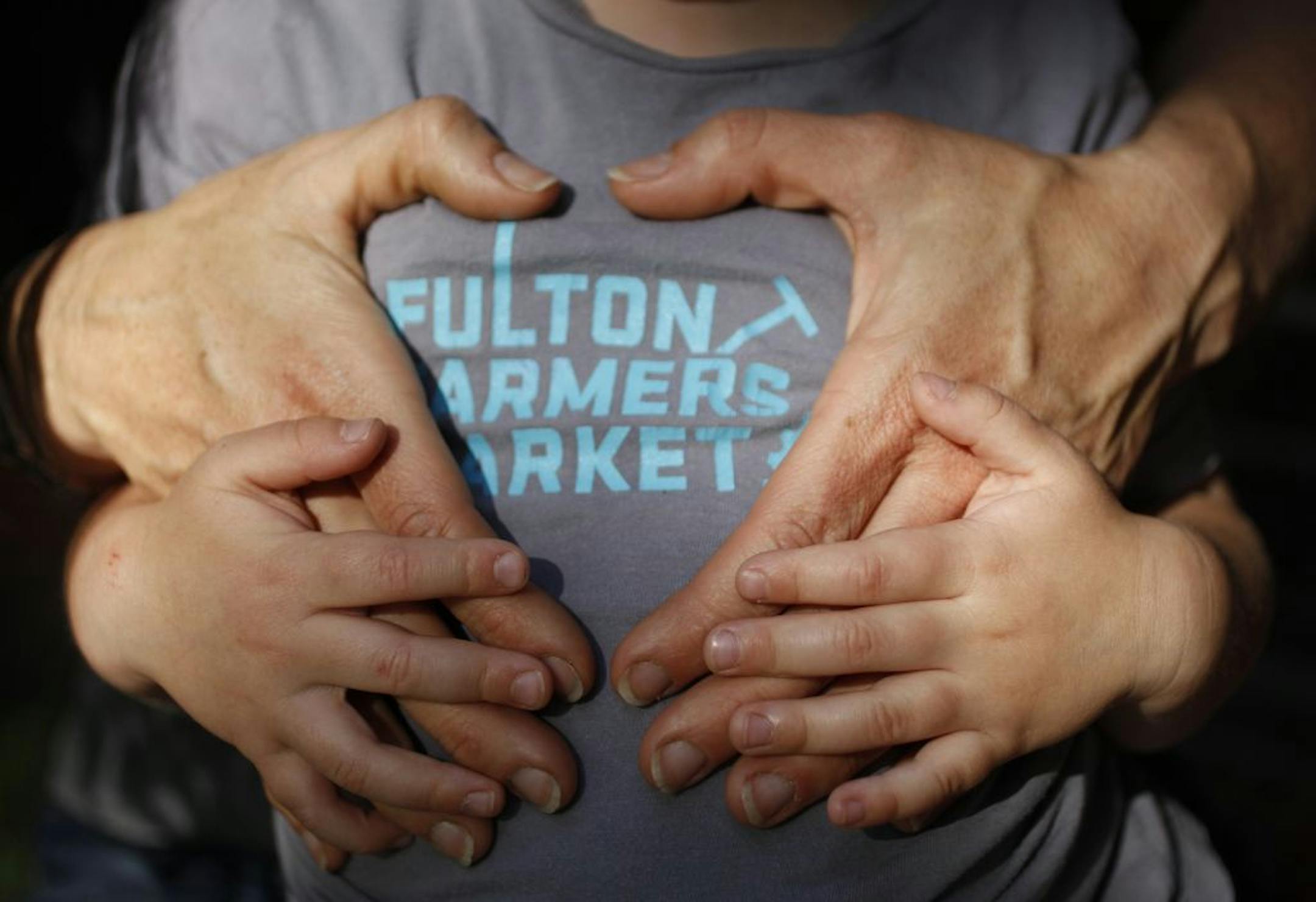 Meg Cowden, Fulton Farmers Market, hugs her son who is wearing the Fulton Market T-shirt.___ For the eighth year of the Taste Special Section called Taste 50, we talk about 50 movers and shakers in the foodie world. Portraits of faces and hands help tell the story of the folks. [ TOM WALLACE • twallace@startribune.com _ Assignments #20023383A_ May12, 28 2012_ SLUG: taste50_0524_ EXTRA INFORMATION: CQ'ed