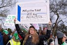 FILE - Abortion-rights activists holds a signs as they protest outside of the Supreme Court during a rally, March 26, 2024, in Washington. A new surve