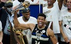 Milwaukee Bucks forward Giannis Antetokounmpo holds up the most valuable player trophy after Game 6 of basketball's NBA Finals against the Phoenix Sun