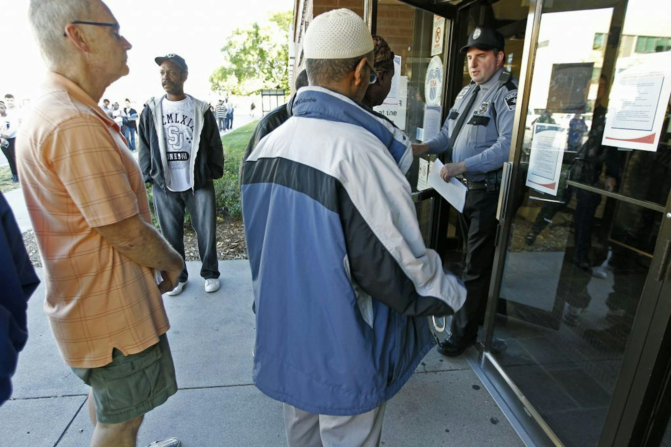 A security guard calms a crowd waiting outside the Social Security Administration Card Center building after they were turned away due to the partial government shutdown, Tuesday, Oct. 1, 2013 in Minneapolis. Many employees classified as nonessential have been idled by the partial federal government shutdown that began early Tuesday. (AP Photo/The Star Tribune, Elizabeth Flores) MANDATORY CREDIT; ST. PAUL PIONEER PRESS OUT; MAGS OUT; TWIN CITIES TV OUT