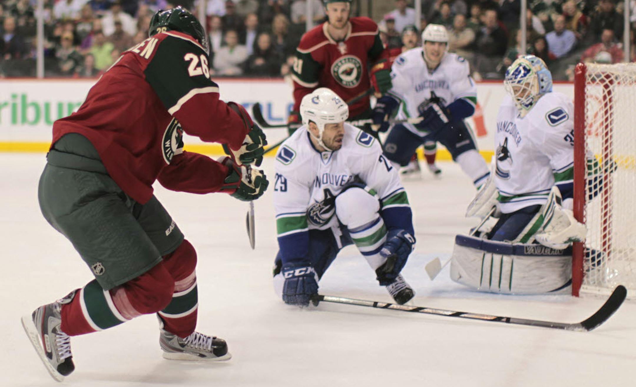 Minnesota's Erik Christensen, left, slipped this first-period shot between Vancouver goaltender Cory Schneider and the left post.