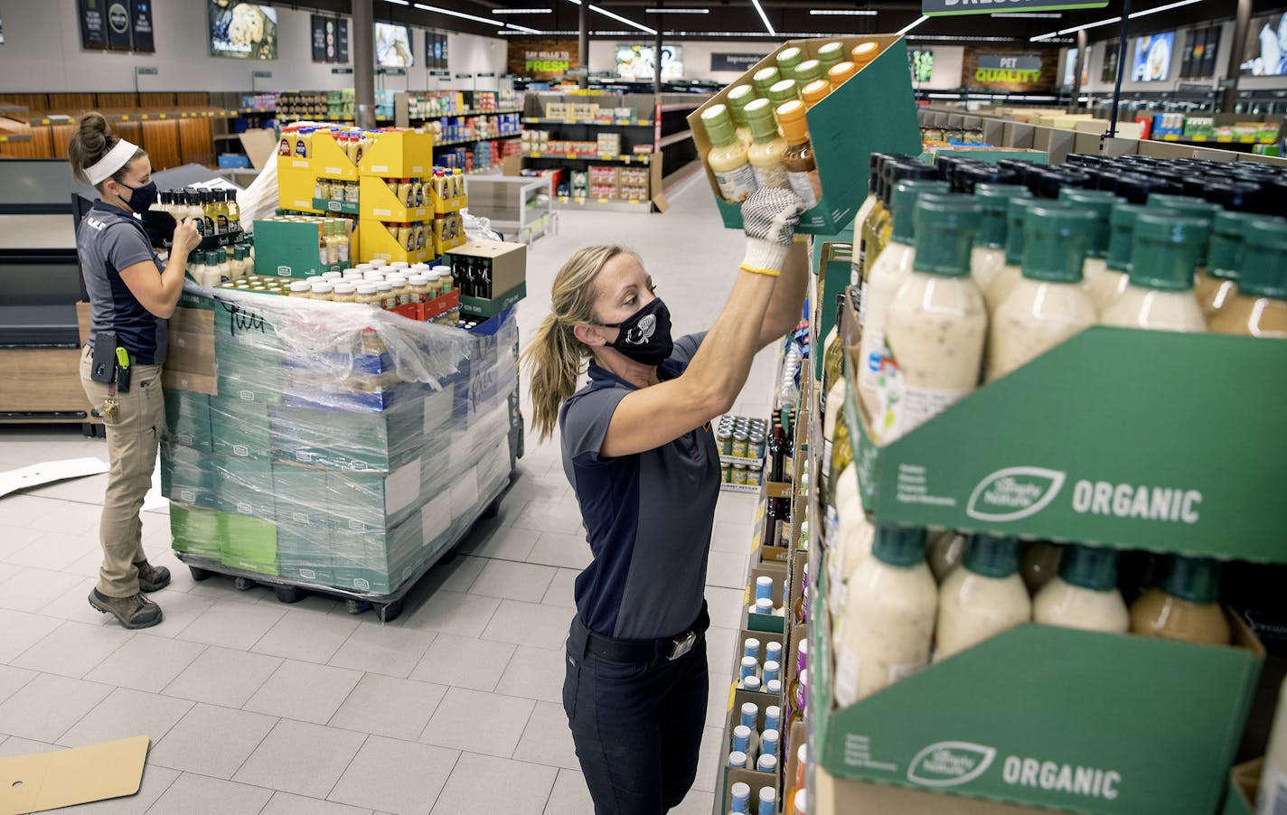 The Aldi grand opening team including Liz Burnard, left, and Gwen Klingelhoets, stocked the shelves in preparation for the 27th Avenue store reopening next week. (ELIZABETH FLORES/Star Tribune)