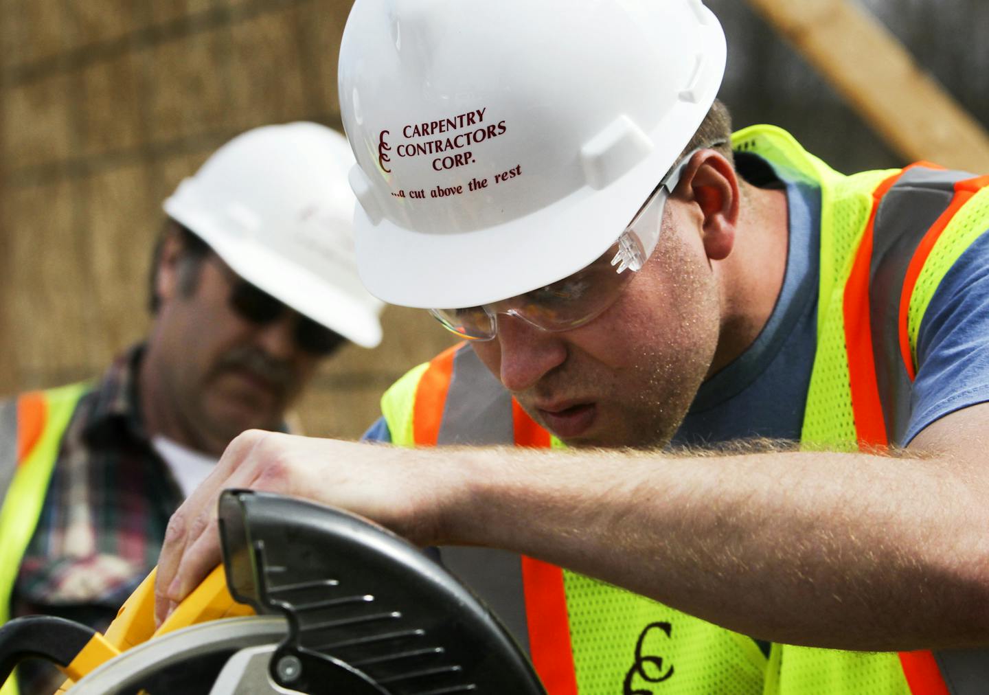 Carpentry Contractors Co.is looking to hire more than 100 workers, but finding people who have the right skills has been difficult. CCC has developed its own training program for carpenters who will build wall panels. They were seen training Tuesday, April 30, 2013, in Montrose, MN. Here, CCC master carpenter and instructor Gene Woodcock, left, watches as participant Josh Fortman, a newly hired carpentry help finisher, sets the angle on a power mitre saw to make an angled cut on a piece of trim