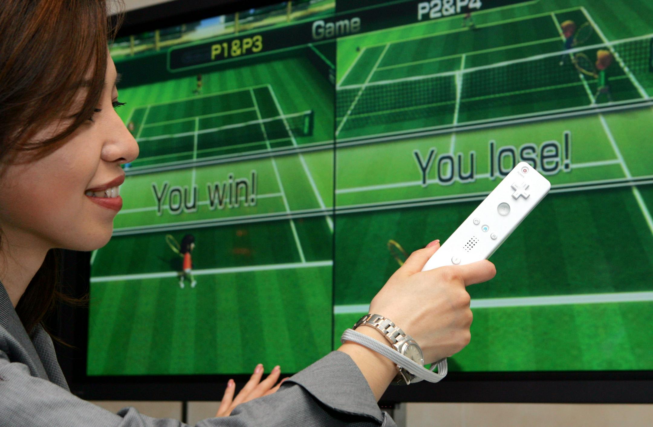 A model plays tennis with Nintendo Co.'s new family video-game console Wii by swinging it's controller as a tennis raquet during a press conference in Tokyo Wednesday, June 7, 2006. Nintendo is sticking with its historical fun-and-games roots as a maker of Japanese-style playing cards as it seeks growth with its next-generation video-game console Wii in a head-to-head battle against rivals Sony and Microsoft.